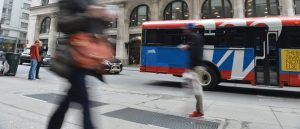 a blurry picture of people crossing the street in front of a bus